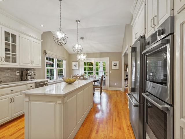 28 Eagle Dr, Fairfield, CT 06825 - kitchen featuring a kitchen island, light wood-type flooring, stainless steel appliances, glass insert cabinets, and vaulted ceiling