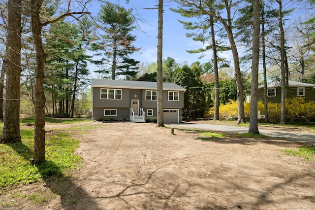 132 Bailey Pond Rd, Voluntown, CT 06384 - bi-level home with dirt driveway, a garage, and view of scattered trees