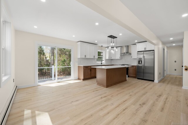 132 Bailey Pond Rd, Voluntown, CT 06384 - kitchen featuring stainless steel fridge, wall chimney range hood, a baseboard heating unit, light countertops, and decorative backsplash