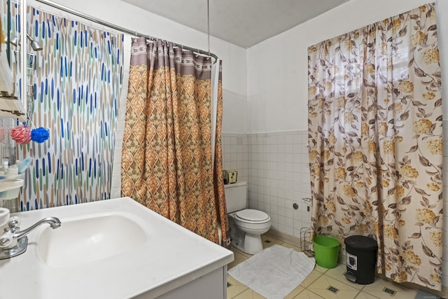 245 Ledyard St, New London, CT 06320 - bathroom with tile patterned floors, tile walls, toilet, vanity, and a wainscoted wall