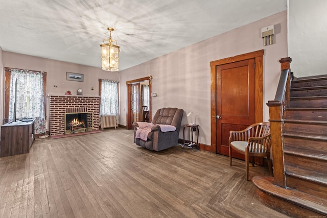 245 Ledyard St, New London, CT 06320 - living area with radiator, hardwood / wood-style flooring, a brick fireplace, stairs, and baseboards