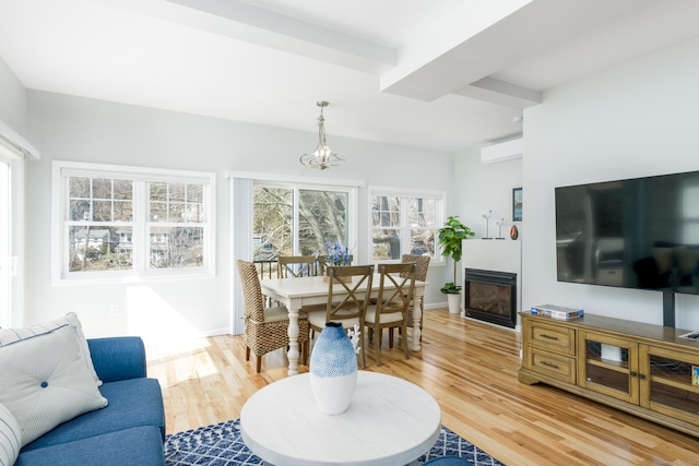 276 Niantic River Rd, Waterford, CT 06385 - living area featuring a wall mounted AC, light wood-style flooring, a glass covered fireplace, and a chandelier