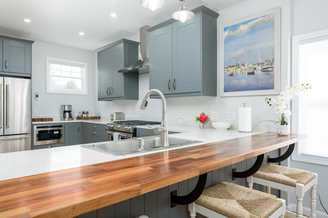 276 Niantic River Rd, Waterford, CT 06385 - kitchen with appliances with stainless steel finishes, wall chimney range hood, recessed lighting, a peninsula, and a breakfast bar