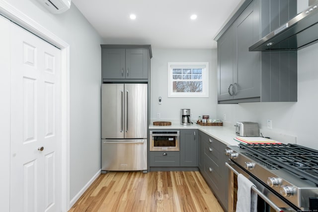 276 Niantic River Rd, Waterford, CT 06385 - kitchen featuring appliances with stainless steel finishes, wall chimney exhaust hood, gray cabinetry, light wood-type flooring, and light countertops