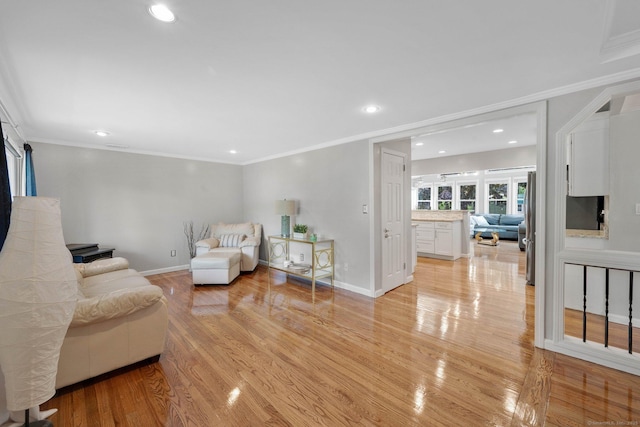living room with light wood finished floors, recessed lighting, crown molding, and baseboards