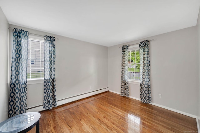 empty room featuring wood finished floors, baseboards, and baseboard heating
