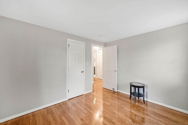 spare room featuring baseboards and light wood-style floors
