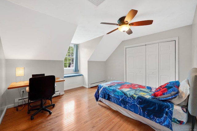 bedroom featuring a baseboard radiator, wood finished floors, baseboards, an office area, and vaulted ceiling