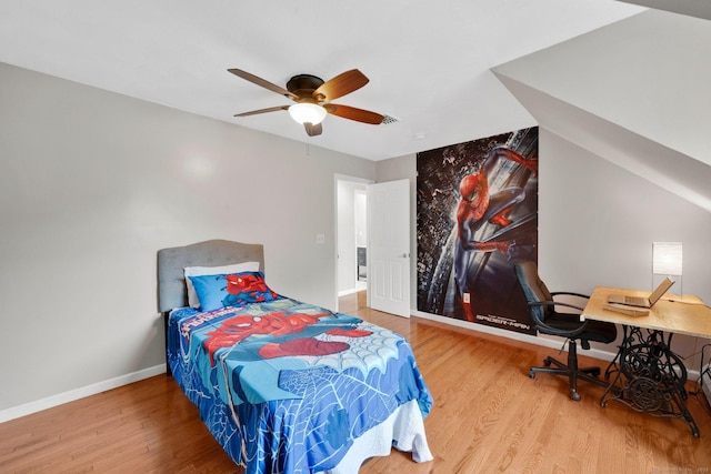 bedroom featuring wood finished floors, baseboards, an office area, and a ceiling fan