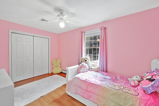 bedroom featuring a baseboard radiator, wood finished floors, a closet, and ceiling fan