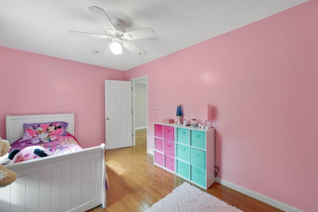 bedroom with light wood finished floors, baseboards, and a ceiling fan