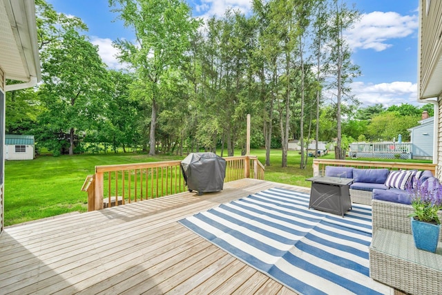 wooden terrace with an outdoor living space, area for grilling, a yard, view of scattered trees, and an outbuilding