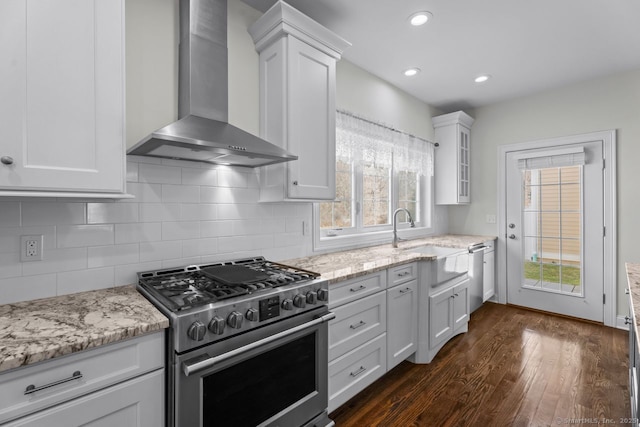 kitchen with wall chimney exhaust hood, appliances with stainless steel finishes, a sink, dark wood-style flooring, and white cabinets