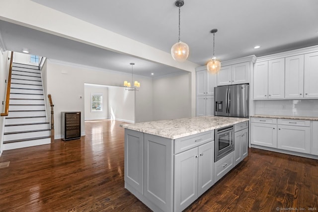 kitchen with appliances with stainless steel finishes, dark wood-type flooring, recessed lighting, decorative light fixtures, and a center island