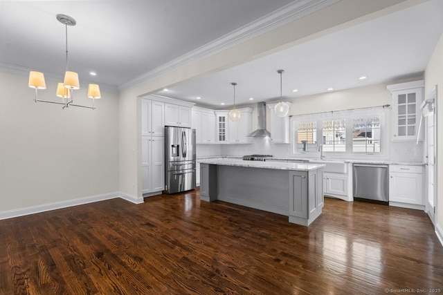 kitchen with stainless steel appliances, wall chimney range hood, glass insert cabinets, white cabinetry, and a kitchen island