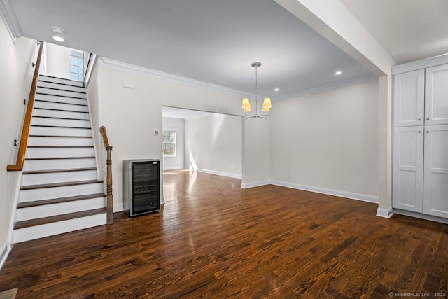 unfurnished living room featuring a chandelier, dark wood-type flooring, baseboards, stairs, and crown molding