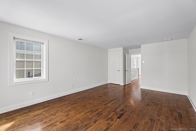 spare room featuring dark wood-style floors and baseboards