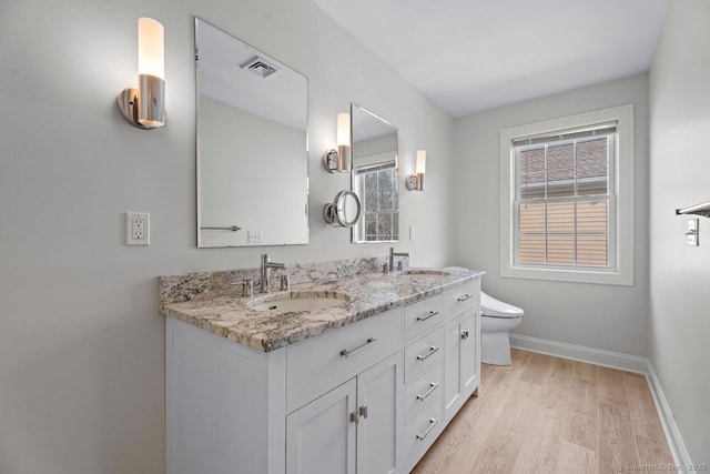 full bath featuring baseboards, wood finished floors, healthy amount of natural light, and toilet