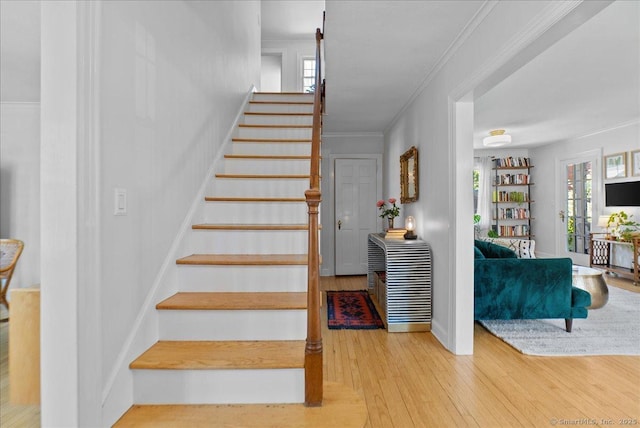 stairway featuring wood finished floors and crown molding