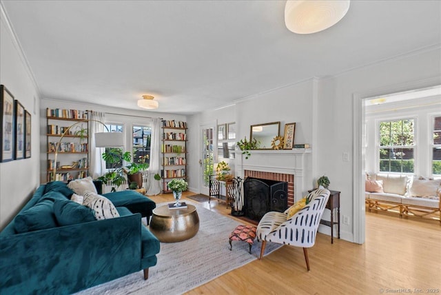 living room with crown molding, wood finished floors, and a brick fireplace