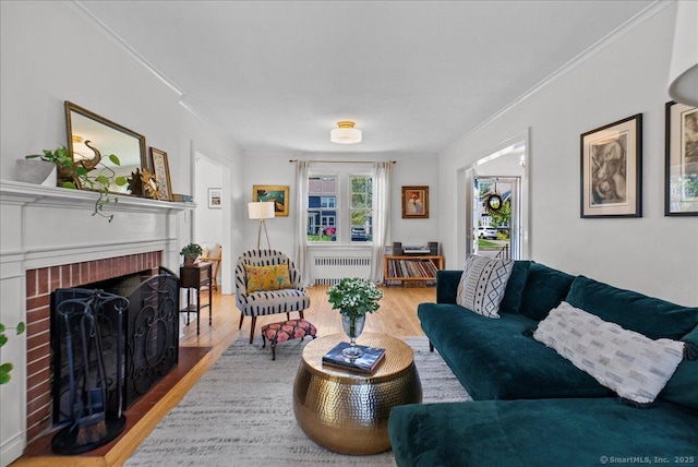 living area featuring radiator heating unit, wood finished floors, ornamental molding, and a brick fireplace
