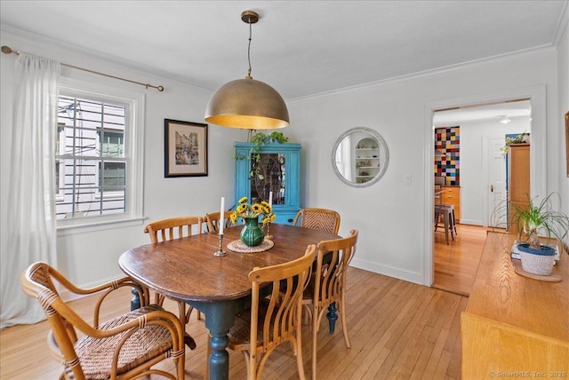 dining area with light wood-style floors, crown molding, and baseboards