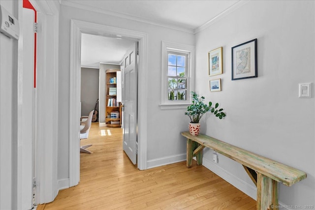 hall featuring ornamental molding, light wood-type flooring, and baseboards