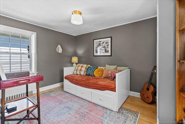 bedroom featuring wood finished floors, baseboards, and crown molding