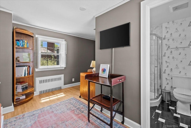 bedroom featuring radiator, crown molding, baseboards, and wood finished floors