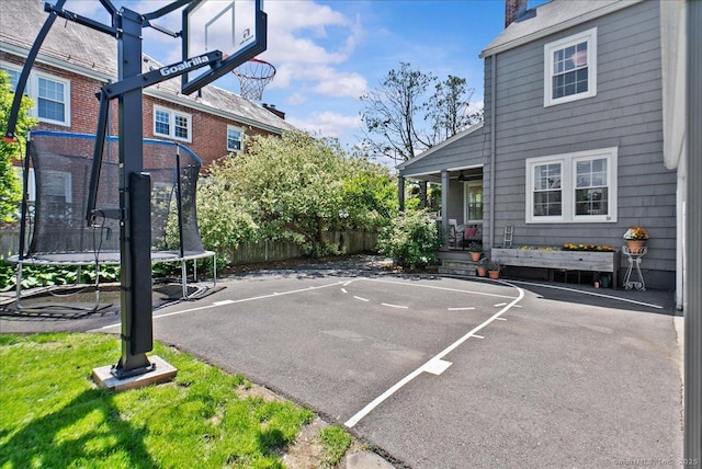 view of basketball court featuring a trampoline and fence