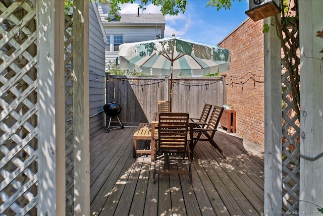 deck with outdoor dining space, grilling area, and fence