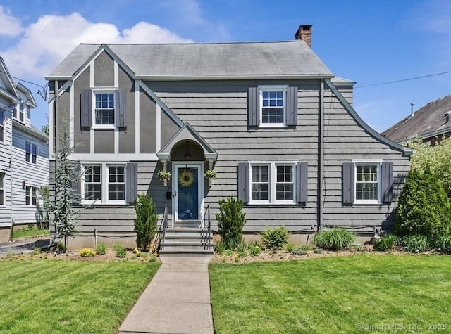 tudor house with a front yard and a chimney