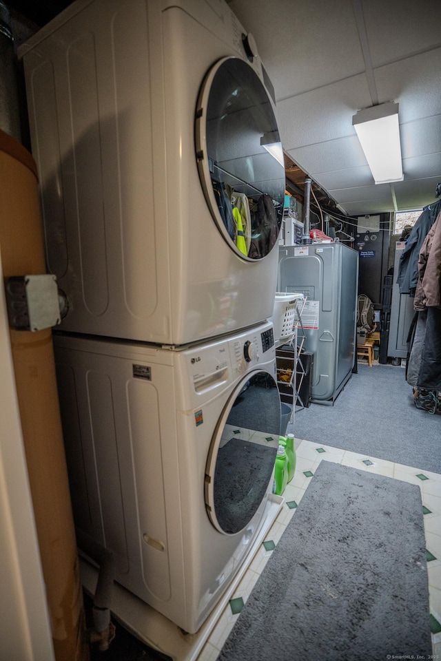 laundry room featuring stacked washer / dryer and carpet