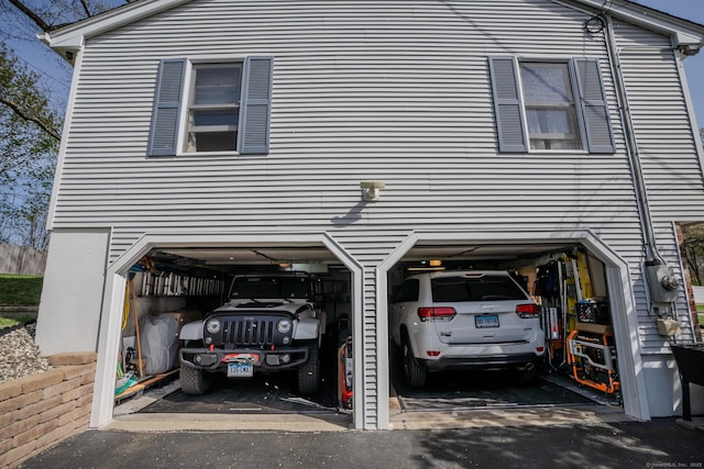 view of side of property featuring an attached garage and asphalt driveway
