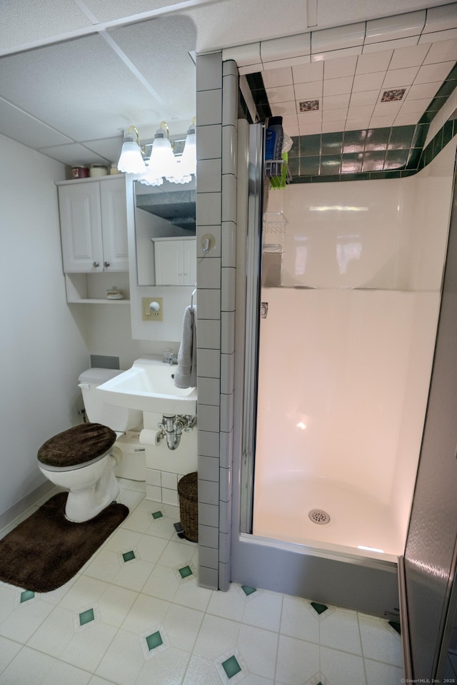 bathroom with a shower stall, tile patterned floors, toilet, and a sink
