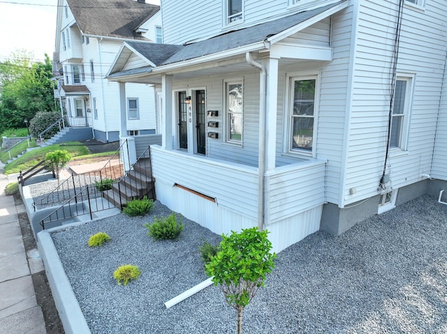 view of side of home featuring a porch and roof with shingles