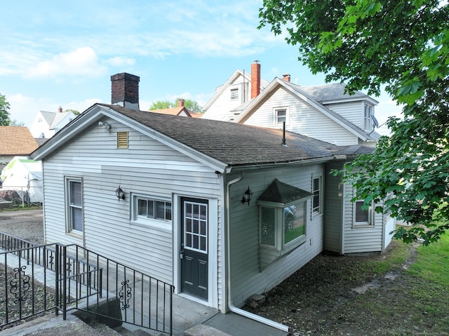 back of house featuring roof with shingles