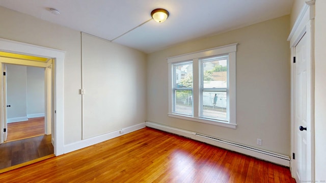 unfurnished bedroom featuring a baseboard radiator, light wood-style floors, and baseboards