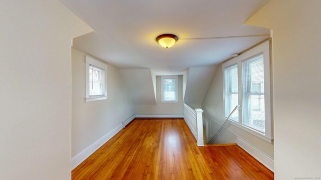 unfurnished room featuring baseboard heating, baseboards, hardwood / wood-style flooring, and plenty of natural light
