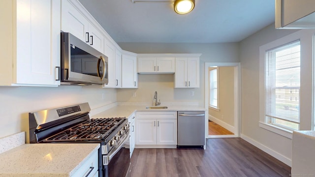 kitchen with stainless steel appliances, a sink, dark wood-style floors, and white cabinetry