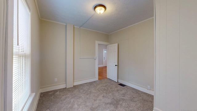 unfurnished bedroom with carpet floors, crown molding, a decorative wall, and a textured ceiling