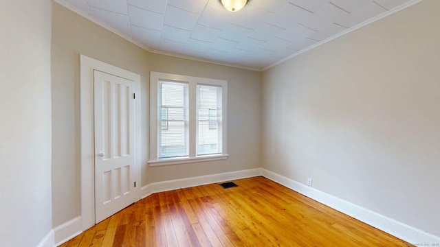 unfurnished room featuring ornamental molding, light wood-style flooring, and baseboards