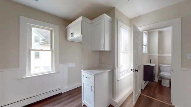 washroom featuring a baseboard radiator, wood finished floors, and a wainscoted wall