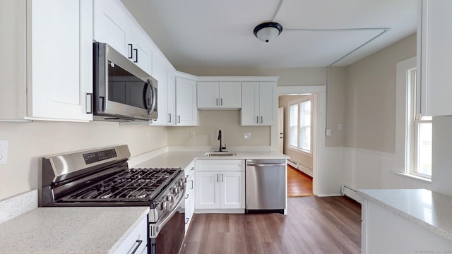 kitchen featuring stainless steel appliances, a sink, dark wood finished floors, white cabinetry, and light stone countertops