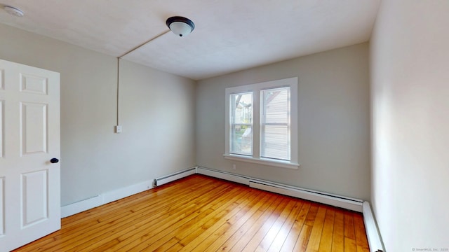 empty room featuring light wood finished floors, a smoke detector, and baseboards
