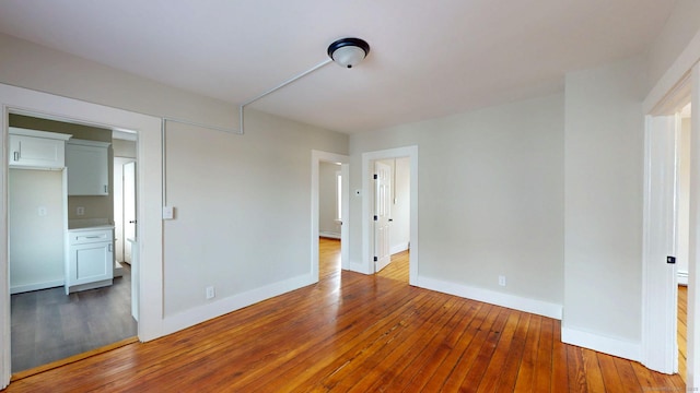 unfurnished room featuring hardwood / wood-style flooring and baseboards