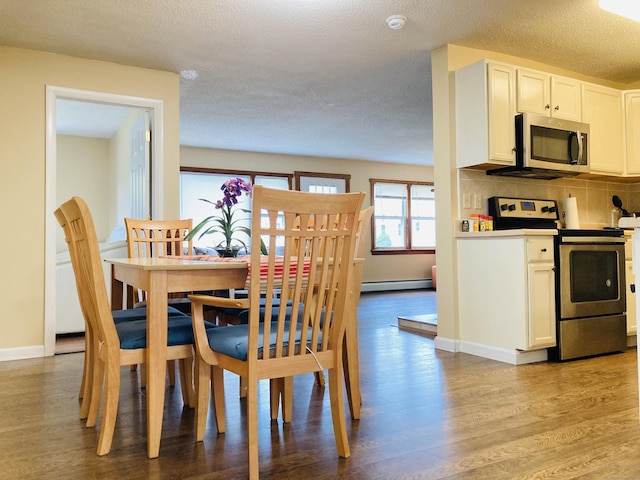 67 S Beechwood Rd, East Lyme, CT 06357 - dining room featuring a baseboard radiator, light wood-style floors, baseboards, and a textured ceiling