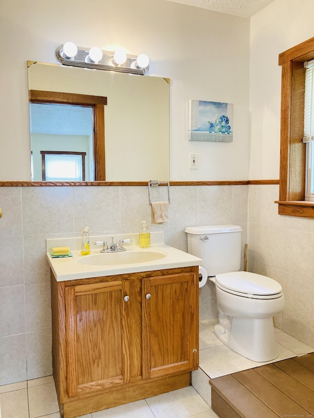 67 S Beechwood Rd, East Lyme, CT 06357 - bathroom featuring tile walls, vanity, tile patterned floors, wainscoting, and toilet