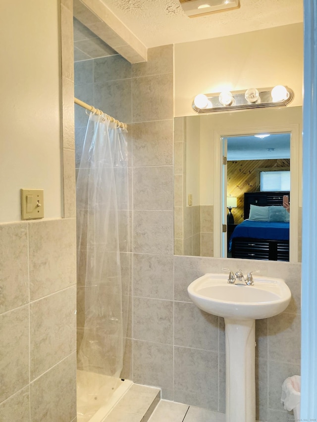 67 S Beechwood Rd, East Lyme, CT 06357 - ensuite bathroom featuring tile walls, a shower stall, tile patterned floors, and a sink