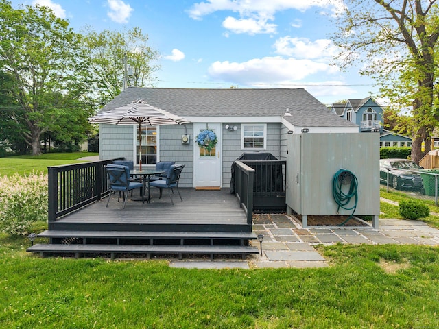 74 Chalker Beach Rd, Old Saybrook, CT 06475 - back of property featuring a wooden deck, a lawn, outdoor dining space, and roof with shingles